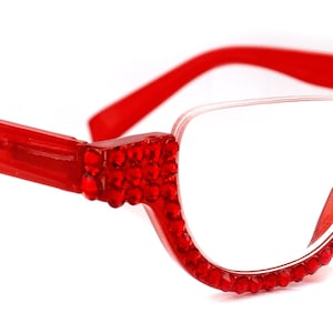 May include: Red plastic framed glasses with clear lenses and red rhinestone accents around the frames.