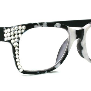 May include: Black and white tortoise shell eyeglasses with rhinestones on the frame. The glasses have clear lenses.