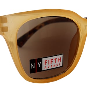 Könnte beinhalten: Eine Sonnenbrille in Bernstein-Farbe mit braunen Gläsern. Die Sonnenbrille hat ein Schildpattmuster an den Bügeln und ein "NY FIFTH AVENUE"-Etikett auf der rechten Linse.