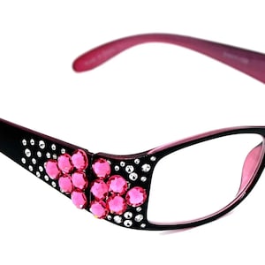 May include: Black and pink reading glasses with rhinestones on the side. The glasses have a clear lens.