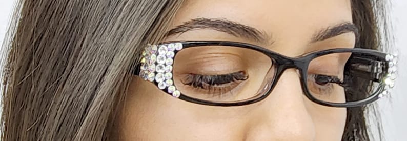 May include: Black cat-eye glasses with rhinestones on the temples. The glasses have clear lenses.