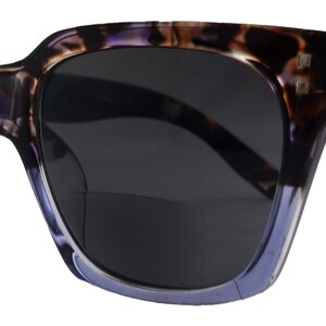 May include: Purple and black tortoiseshell sunglasses with dark lenses. The sunglasses have a square frame and the brand name "Fifth Avenue" is printed on the left lens.