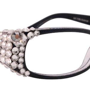 May include: Black cat-eye spectacles with clear lenses. The frames are adorned with clusters of clear rhinestones on the outer edges. The temples are sleek and black, adding a touch of elegance to the design.