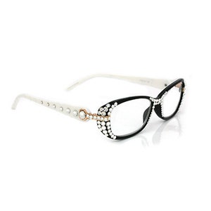 Könnte beinhalten: Weiße und schwarze Brille mit Strasssteinen um die Rahmen. Die Gläser sind klar.