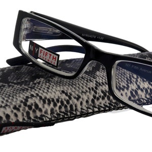 Op de afbeelding: Zwarte rechthoekige leesbril met heldere glazen en +1,00 dioptrie. De bril ligt naast een etui met slangenprint. De merknaam "NY Fifth Avenue" is zichtbaar.