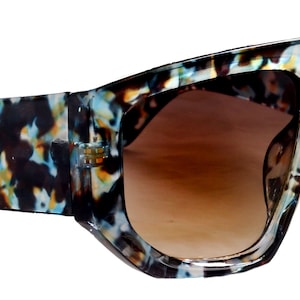 Könnte beinhalten: Überdimensionale Sonnenbrille mit einem Schildpattmuster-Rahmen und braunen Gläsern.