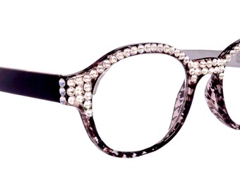 Puede incluir: Gafas de carey negro y gris con un borde de diamantes de imitación alrededor de las lentes.