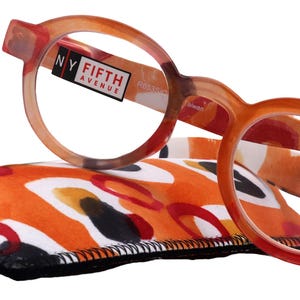 Puede incluir: Gafas de lectura de carey naranja y marrón con una funda estampada en blanco y negro. Las gafas tienen una lente de +3,00 y la marca "NY Fifth Avenue" está impresa en el lateral.