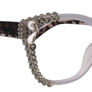 Könnte beinhalten: Brille im Cat-Eye-Stil mit einem hellgrauen Rahmen und Leopardenmuster-Bügeln. Der Rahmen ist mit Strasssteinen verziert. Die Brille ist für Mode und Sehkorrektur konzipiert.