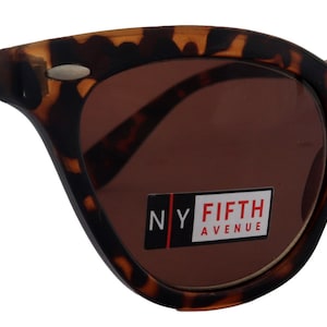 May include: Tortoise shell cat eye sunglasses with brown lenses. The sunglasses have the text "NY FIFTH AVENUE" on the right lens.
