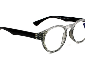 Puede incluir: Gafas de lectura de plástico gris con patillas negras y pedrería alrededor de las lentes. Las gafas tienen una graduación de +2,50 y un puente de 16 mm.