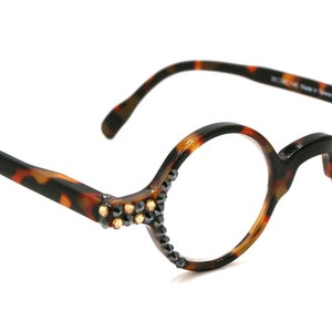 May include: Tortoise shell reading glasses with round lenses and rhinestones on the temples. The glasses have a +3.00 magnification and a 13 size.