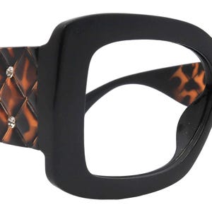 May include: Black square-framed eyeglasses with a tortoise shell pattern on the temples. The temples are adorned with clear rhinestones. The interior of the frame also features the tortoise shell pattern. The glasses have a bold, retro style.