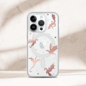 May include: A clear phone case for an iPhone featuring a rose gold dragon pattern with small star accents. The case includes a circular magnetic charging ring on the back and a cutout for the triple camera lens system on the top left corner.
