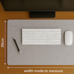 May include: A gray rectangular desk mat with a white keyboard, mouse, and pen. The mat is 13.8 inches wide and has the text "width made to measure". The keyboard and mouse are white.