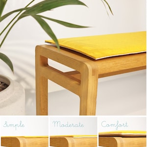 Puede incluir: Un banco de madera con un coj&iacute;n amarillo brillante. El banco es de madera clara y tiene un dise&ntilde;o simple y moderno. El coj&iacute;n es rectangular y parece estar hecho de un material suave. El banco est&aacute; colocado frente a un fondo blanco.