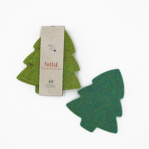 Könnte beinhalten: Set mit vier grünen Filz-Weihnachtsbaum-Untersetzern. Die Untersetzer sind aus Filz und haben ein schlichtes, klassisches Design. Die Untersetzer sind in einem braunen Karton verpackt, auf dem der Markenname "feltd. Feltdesign" aufgedruckt ist.