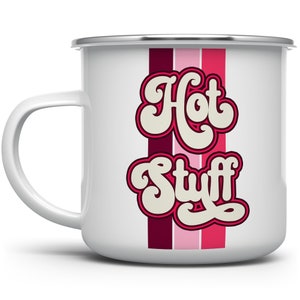 May include: White enamel mug with a silver rim and handle. The mug features the words "Hot Stuff" in a retro font with a pink outline, set against vertical stripes of burgundy, pink, and fuchsia.