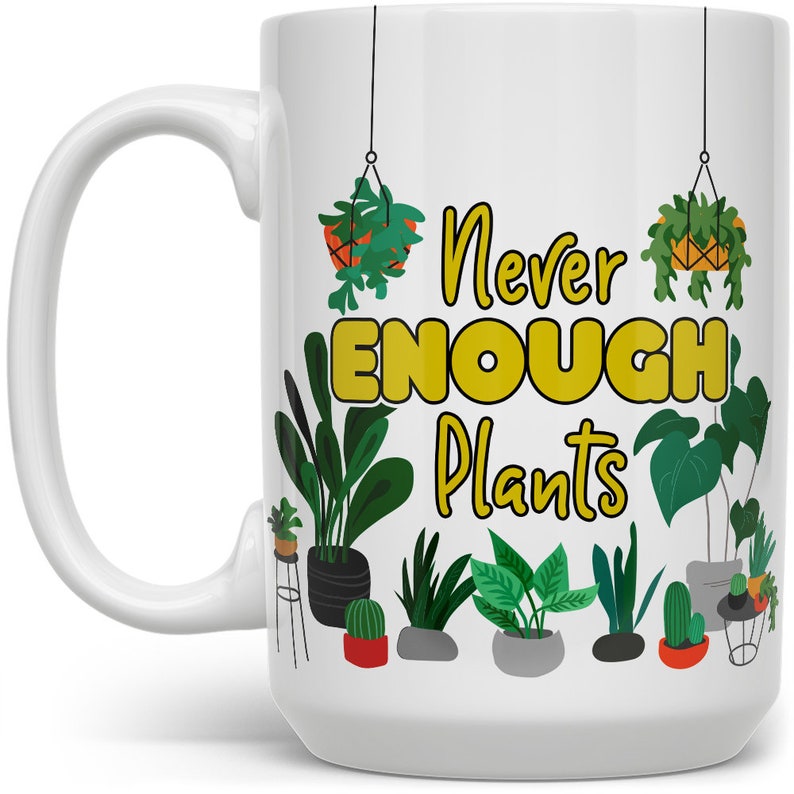 Puede incluir: Taza de caf&eacute; de cer&aacute;mica blanca con un dise&ntilde;o verde y amarillo. La taza presenta una variedad de plantas en maceta y el texto "Never Enough Plants".