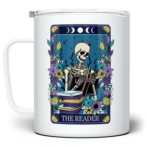 May include: White ceramic mug with a colorful illustration of a skeleton reading a book. The illustration is surrounded by flowers and the text "THE READER".