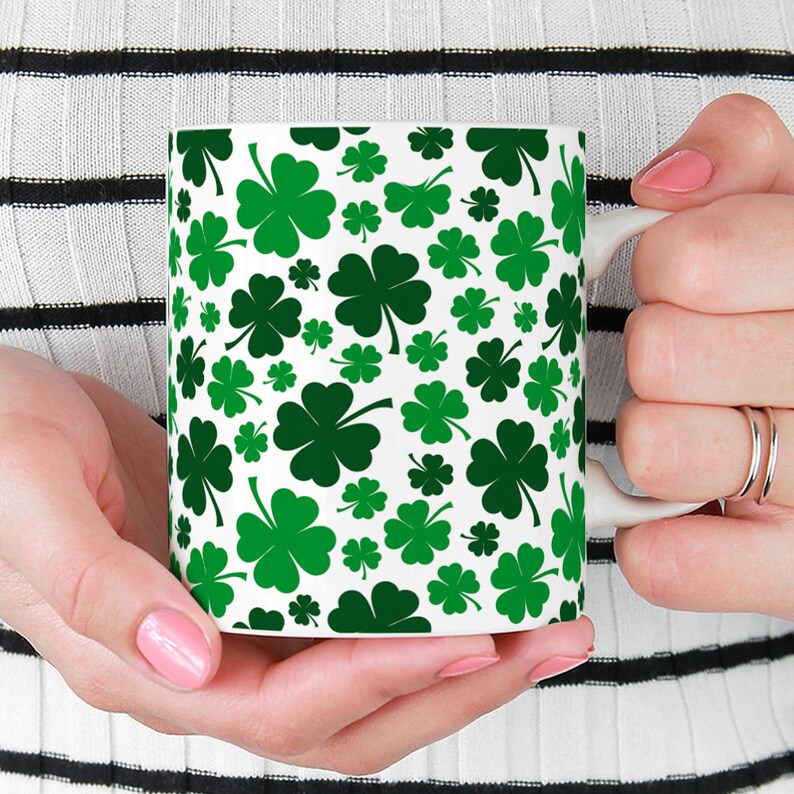 May include: White ceramic mug with a green four-leaf clover pattern.