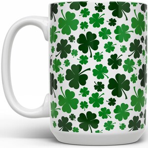 May include: White ceramic mug with a green four-leaf clover pattern.