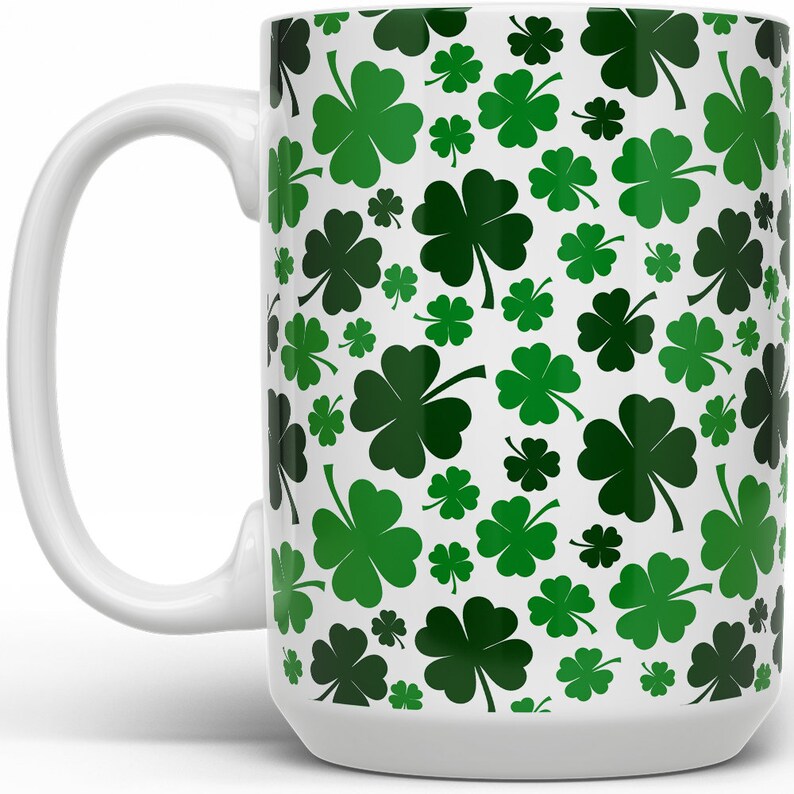 May include: White ceramic mug with a green four-leaf clover pattern.