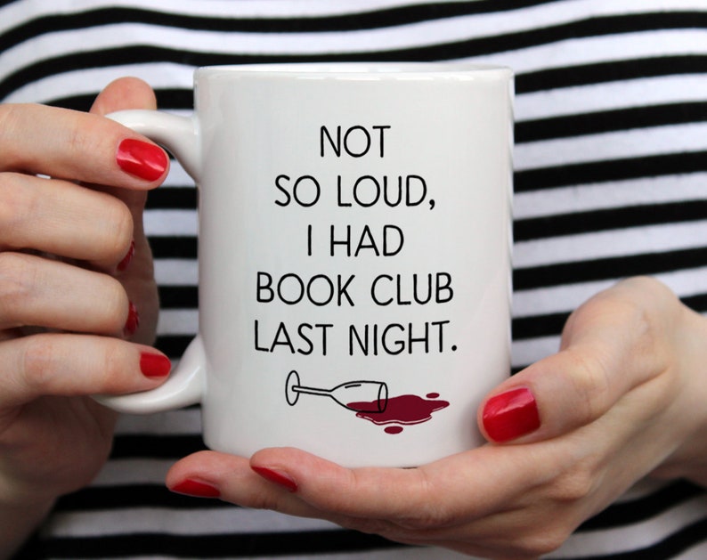 May include: White ceramic mug with black text that reads "Not so loud, I had book club last night." A black and white illustration of a wine glass with red wine spilled on the white surface.