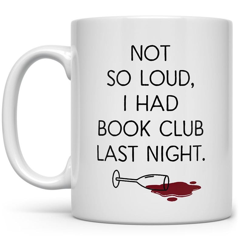 May include: White ceramic coffee mug with black text that reads "Not so loud, I had book club last night." A cartoon image of a wine glass with red wine spilled on the white surface.
