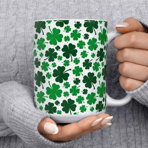 May include: White ceramic mug with a green four-leaf clover pattern.