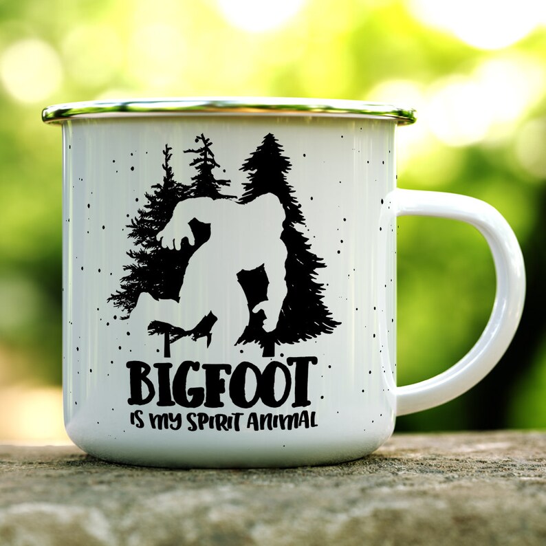 May include: White enamel camping mug with a black silhouette of Bigfoot walking through a forest. The text "BIGFOOT is my spirit animal" is printed below the image.