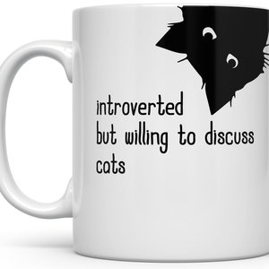 May include: White ceramic mug featuring a black cat design and the words "introverted but willing to discuss cats." The mug has a curved handle and is suitable for hot drinks. A humorous gift for cat enthusiasts.