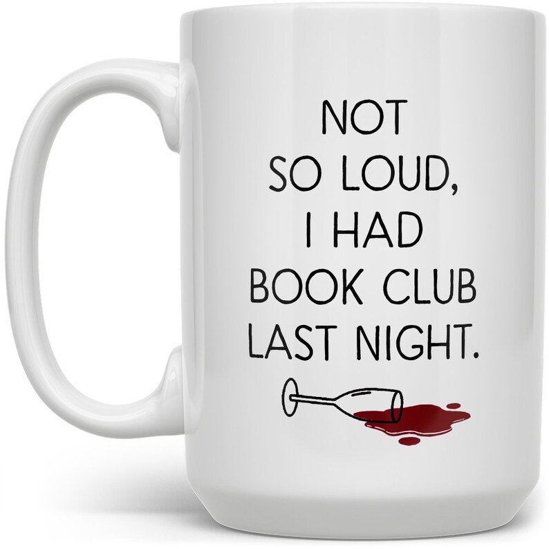 May include: White ceramic coffee mug with black text that reads "Not so loud, I had book club last night." A black and white illustration of a wine glass with red wine spilled on the white surface.