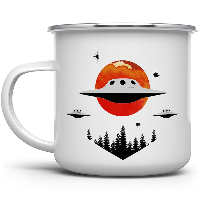May include: White enamel mug featuring a graphic of a flying saucer over a red sun with a forest silhouette below. The saucer has three small windows and is flying over a red sun with orange clouds. The forest silhouette is black and has a triangular shape.