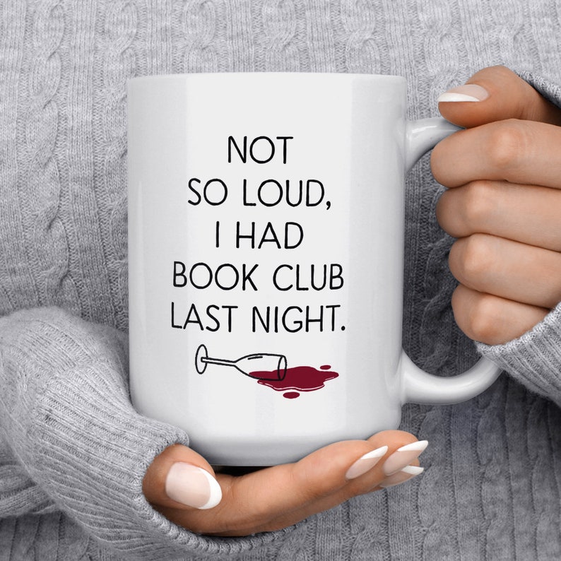 May include: White ceramic coffee mug with black text that reads "NOT SO LOUD, I HAD BOOK CLUB LAST NIGHT."  A black and white illustration of a wine glass with red wine spilled on the white surface.