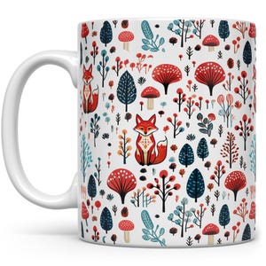 May include: White ceramic mug with a repeating pattern of red foxes, red and blue trees, and red mushrooms on a white background.