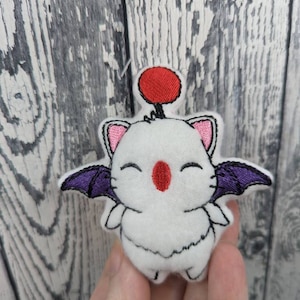May include: White plush toy with purple wings and a red ball on its head. The toy has a smiling face with red cheeks and a pink nose.