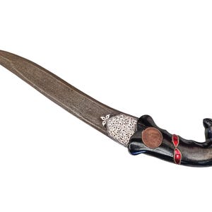 Könnte beinhalten: Ein schwarz-silbernes, verziertes Dolch mit einem rot-schwarzen Griff. Der Griff ist in Form eines Vogelkopfes gestaltet.