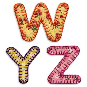 May include: Three fabric letters, W, Y, and Z, are stitched together with colorful thread. The W is yellow with orange thread and a floral pattern. The Y is yellow with purple thread. The Z is pink with red thread.