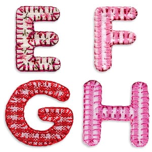 May include: Four fabric letters, E, F, G, and H, in pink and red with white accents. The letters are stitched with a white thread and have a patchwork design.