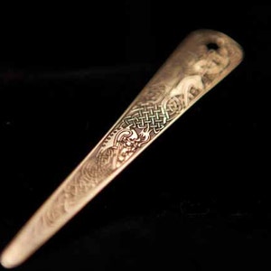 Puede incluir: Un peine de pelo largo y delgado de metal dorado con un intrincado dise&ntilde;o de nudo celta.