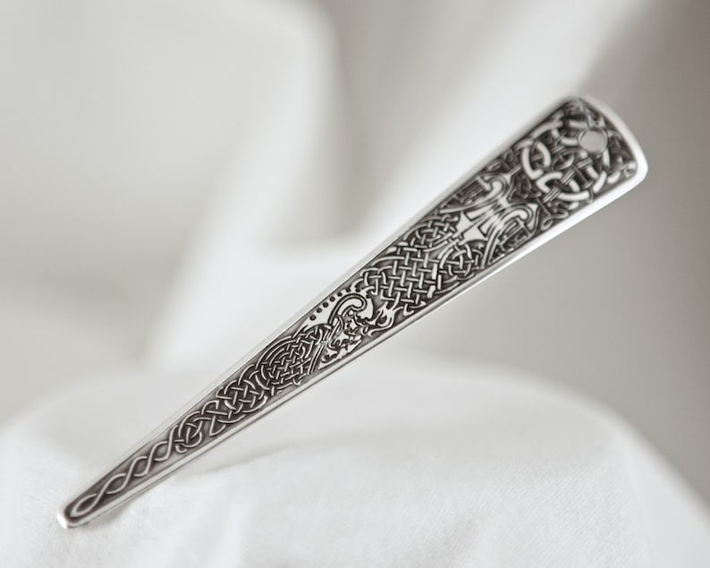Puede incluir: Un peine de pelo de plata con un intrincado dise&ntilde;o de nudo celta.
