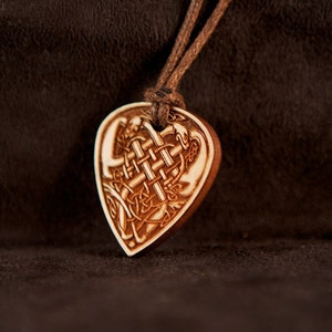 May include: A wooden heart-shaped pendant with a Celtic knot design and a brown leather cord.
