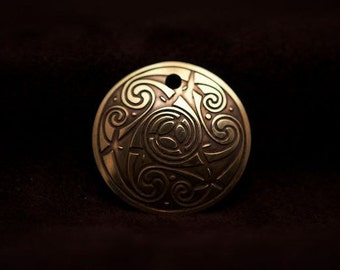 Colgante en espiral de arte celta, grabado en latón del Libro de Kells, fabricado en Irlanda.