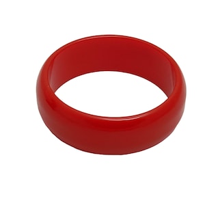 May include: A bright red plastic bangle bracelet. The bracelet is smooth and shiny.