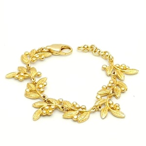 May include: Gold-toned bracelet featuring a leaf and berry design. The bracelet has a lobster clasp closure and is composed of multiple leaf and berry clusters connected by small chain links. The leaves and berries are detailed with textured surfaces.