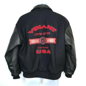May include: Black jacket with leather sleeves. The back of the jacket features the word "VOLANT" in red, along with "LIMITED EDITION", "UNIQUE QUALITY", "US PATENT 4966545", and "USA".