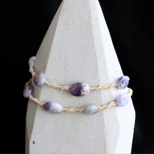 Può includere: Una collana a doppio filo con perline di ametista ovali di colore viola chiaro e bianco e un cordoncino color crema.