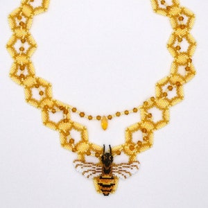 May include: A gold and yellow beaded necklace featuring a bee pendant. The necklace is crafted from small, hexagonal beads and has a delicate, intricate design. The bee pendant is detailed and realistic, with black and yellow stripes and white wings.