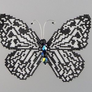 May include: A black and white beaded butterfly with iridescent blue and black crystal accents.